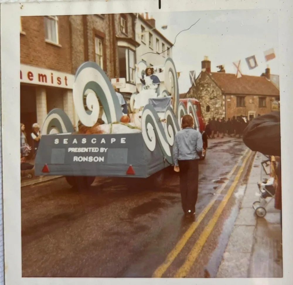 Colour photograph of the rear of the Ronson ‘Seascape presented by Ronson’ carnival float travelling down Newport High Street, with crowds lining the pavement.